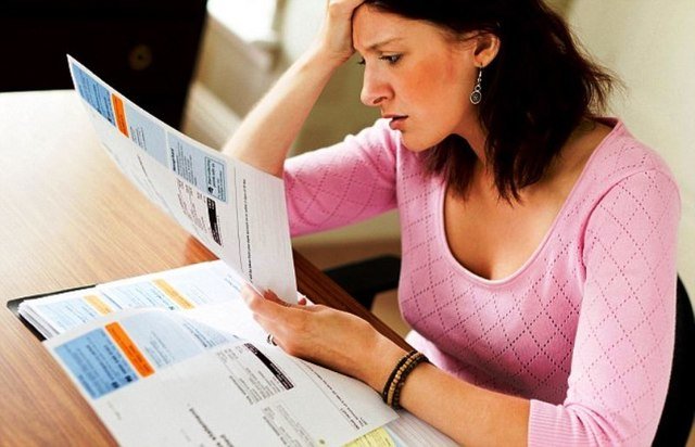 Woman in pink sweater stressed while looking at utility bills