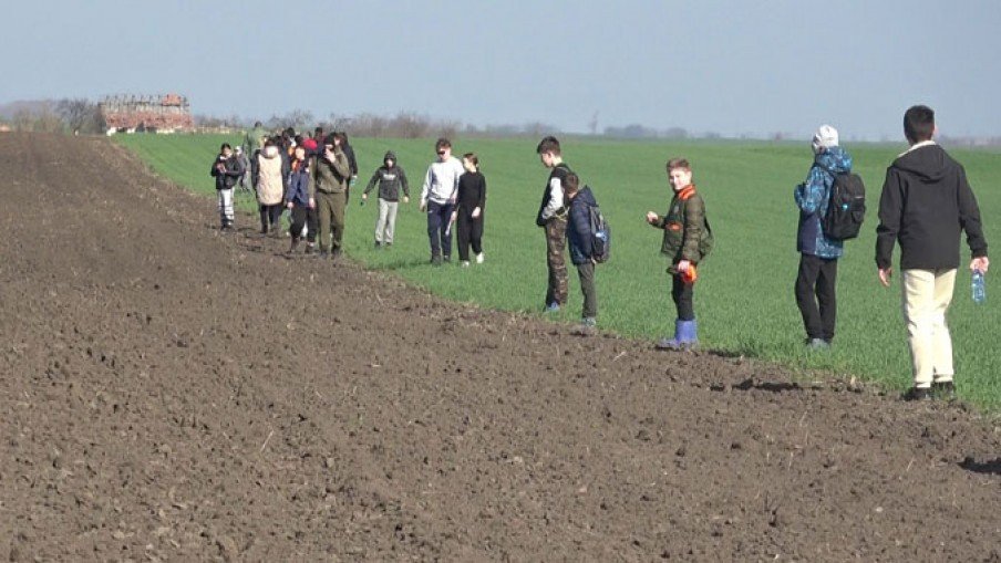 Школьники идут вдоль вспаханного поля на экскурсии по подсчёту зайцев в окрестностях Кикинды