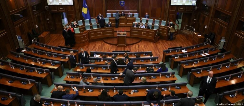 Зал заседаний парламента Косово: многие места пусты, депутаты собираются в центре зала