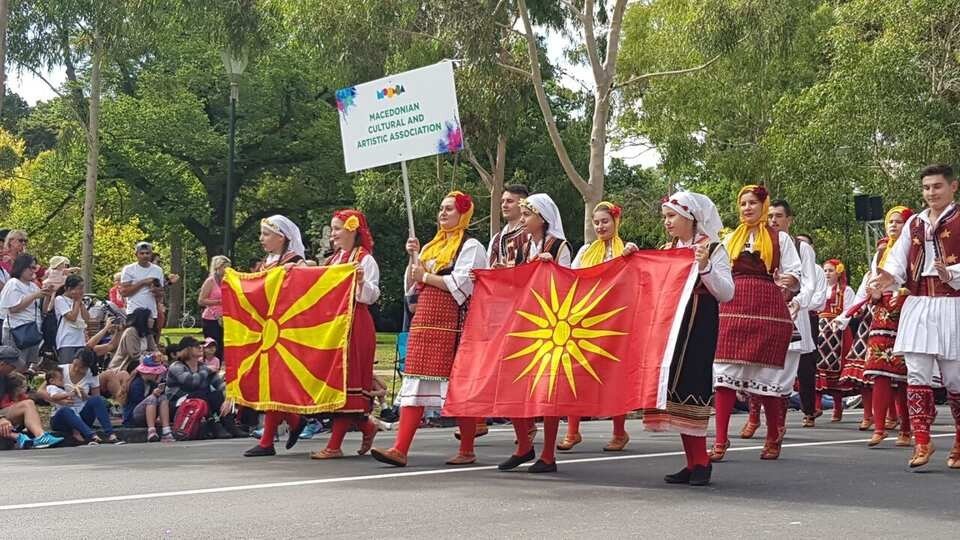 Участники Македонской культурно-художественной ассоциации на параде Мумба в Мельбурне несут государственный флаг и флаг с Кутлешским солнцем в национальных костюмах