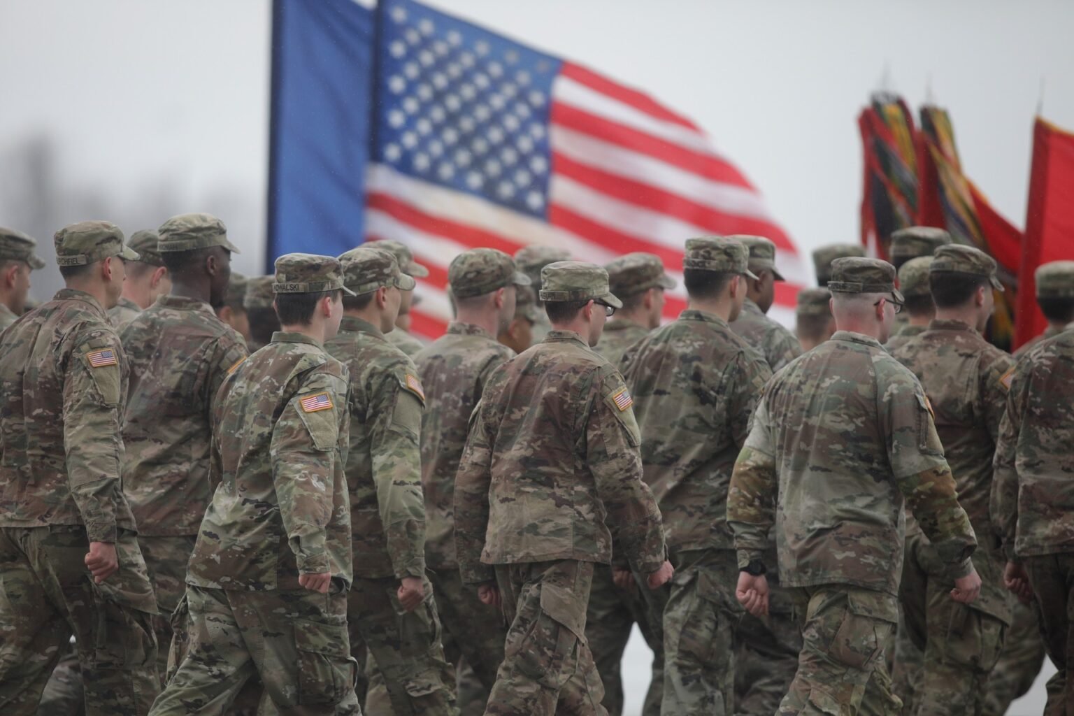 Американские военнослужащие маршируют на фоне флага США во время церемонии на военной базе в Румынии