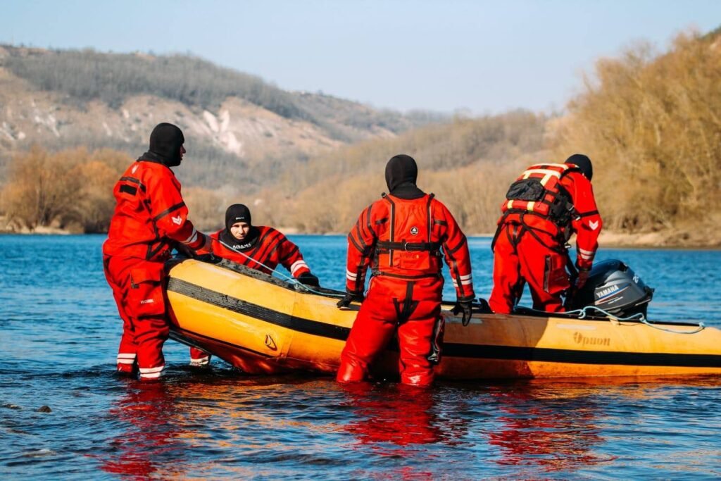 Спасатели в защитных костюмах готовят надувную лодку для работы на Днестре во время экологической тревоги