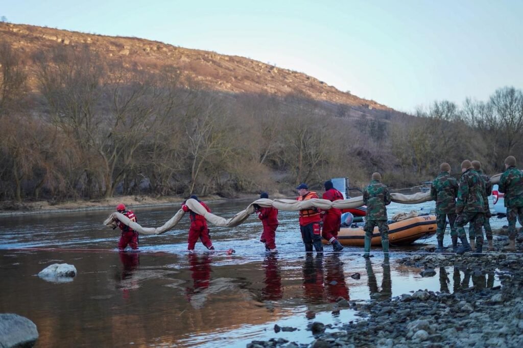 Нефть в Днестре: удар РФ отравил воду Молдовы Спасатели в красных комбинезонах несут боновое заграждение через воды Днестра для локализации нефтяного загрязнения