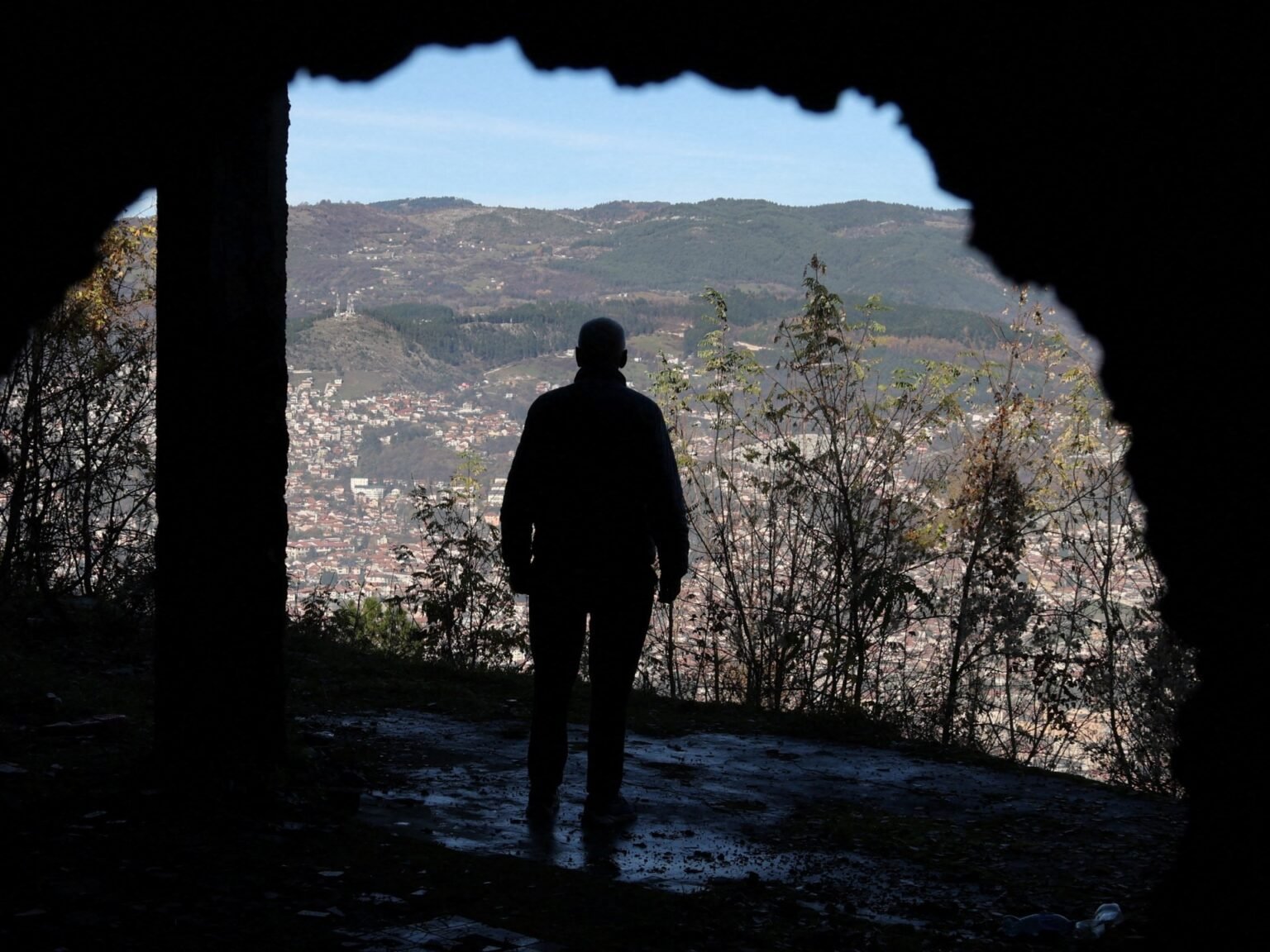 Силуэт человека на бывшей снайперской позиции с видом на долину Сараево — место, откуда во время осады иностранные «охотники» стреляли по мирным жителям