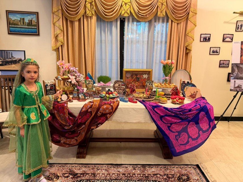 Новруз в Куала-Лумпуре: как азербайджанцы встретили весну вдали от дома Девочка в зелёном национальном платье рядом с праздничным столом Новруза