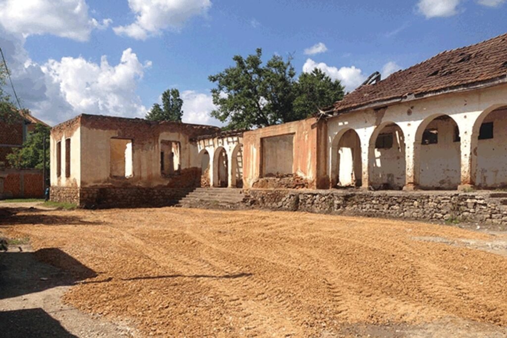 Руины Дома культуры в Рунике (Косово) — полуразрушенный арочный фасад и внутренний двор здания, ожидающего ревитализации