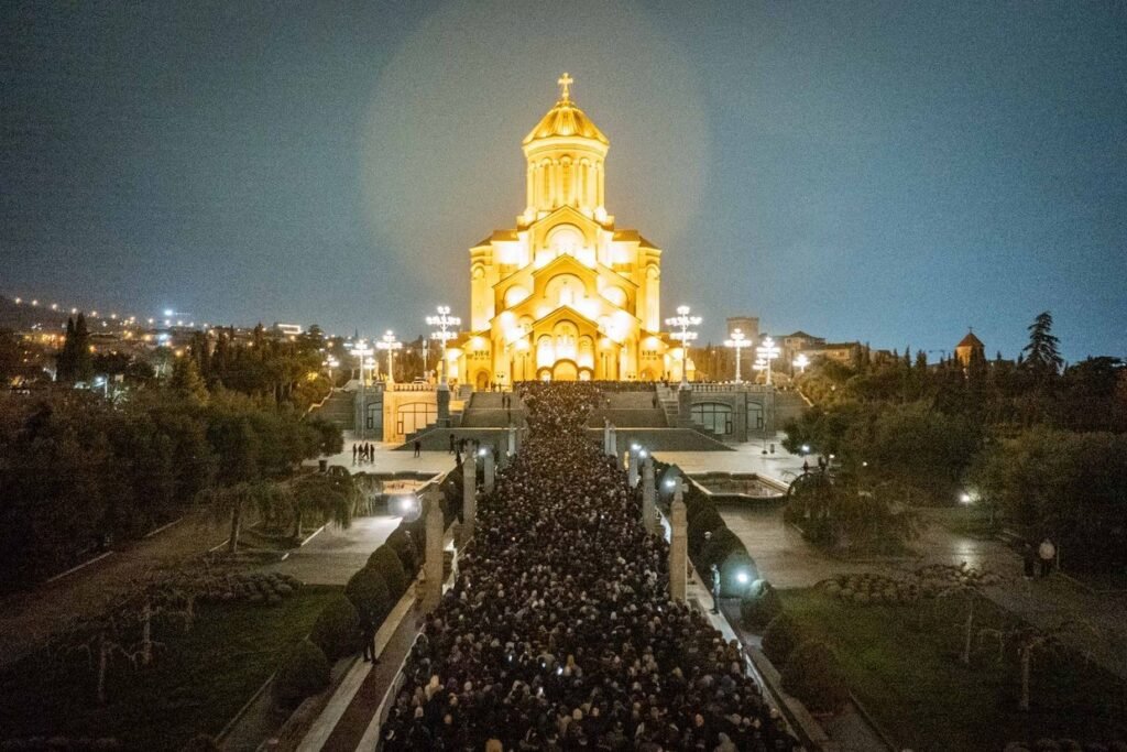 Грузия прощается с Патриархом Илией II: конец 48-летней эпохи Собор Святой Троицы (Самеба) в Тбилиси, освещённый золотым светом ночью, с огромной толпой верующих, стекающихся к храму для прощания с Патриархом Илией II