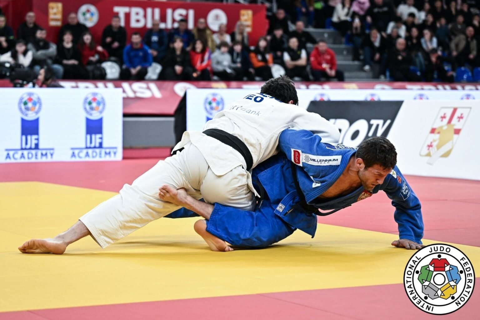 Тбилиси примет чемпионат Европы по дзюдо в апреле 2026 Два дзюдоиста в напряжённой борьбе на татами во время Tbilisi Grand Slam 2026. На заднем плане — надпись «TBILISI» и баннеры IJF Academy