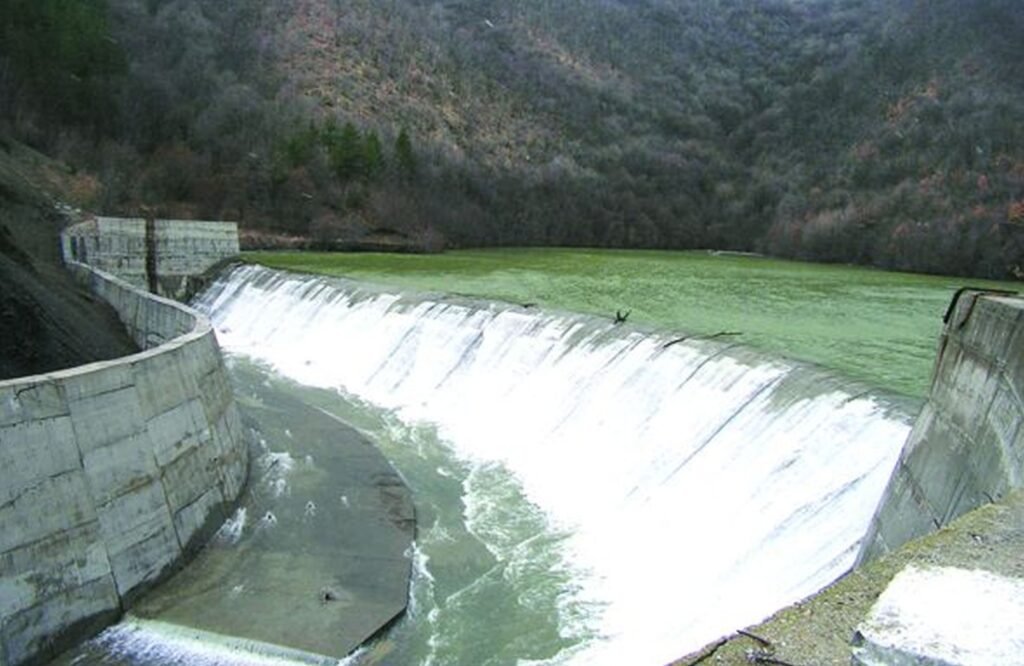 Переливающийся язовир в Болгарии — вода стекает через водосброс плотины после обильных осадков
