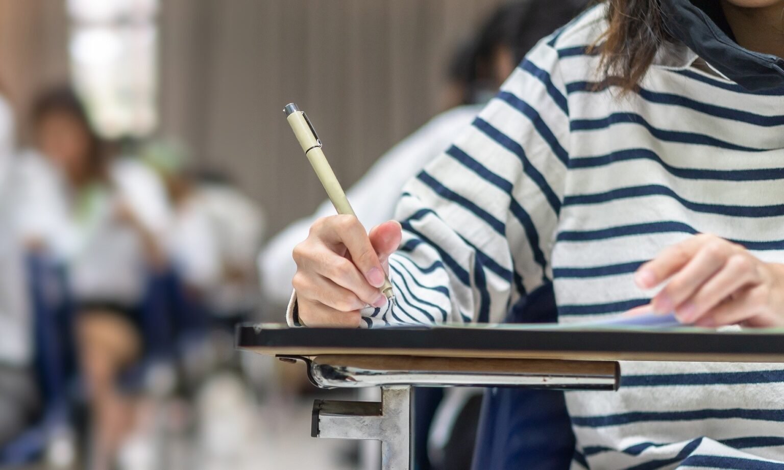 Ученица пишет экзаменационную работу за партой в школьном классе