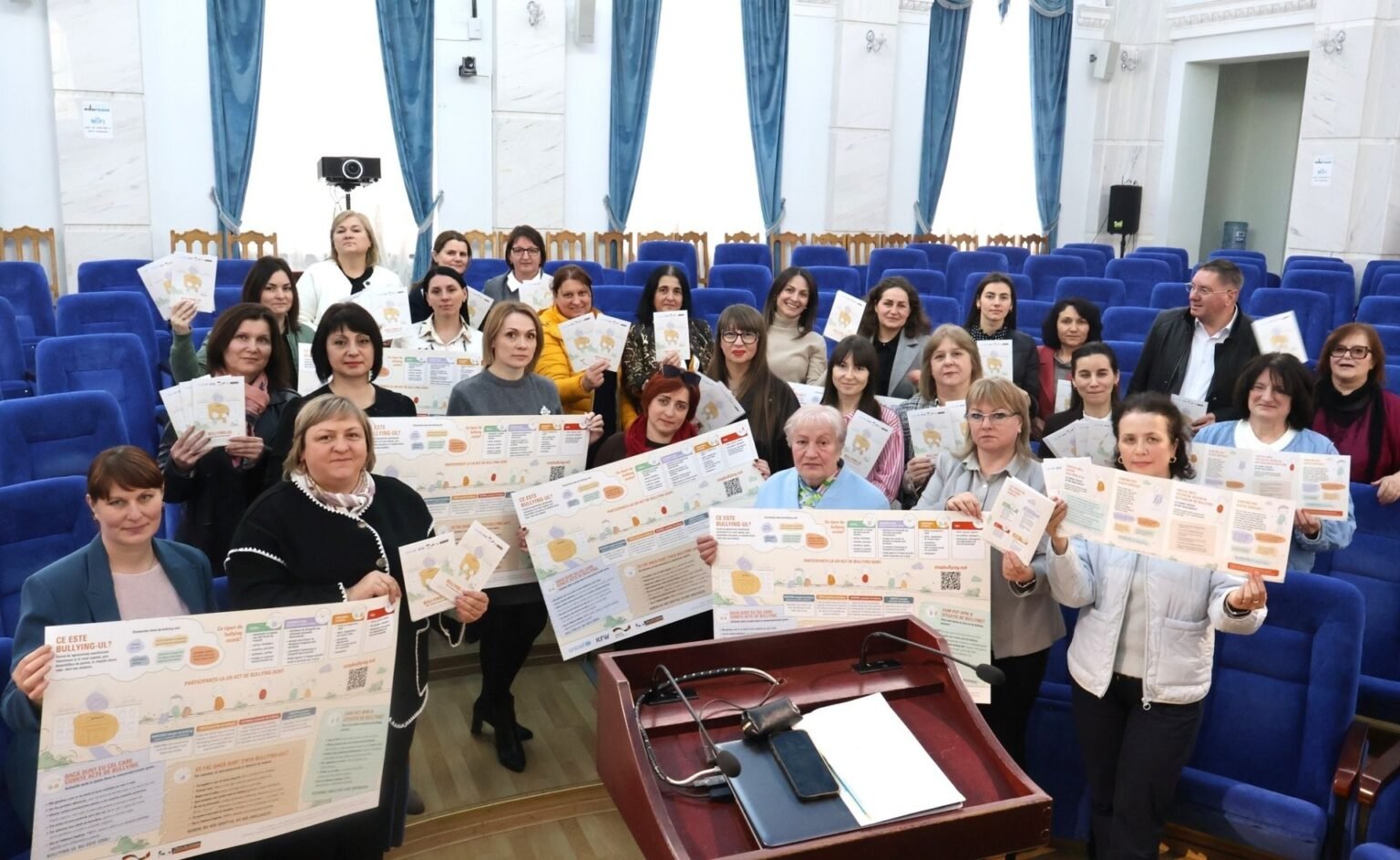 Участники рабочей группы по разработке национального плана борьбы с буллингом держат информационные плакаты в конференц-зале Министерства образования и науки Молдовы