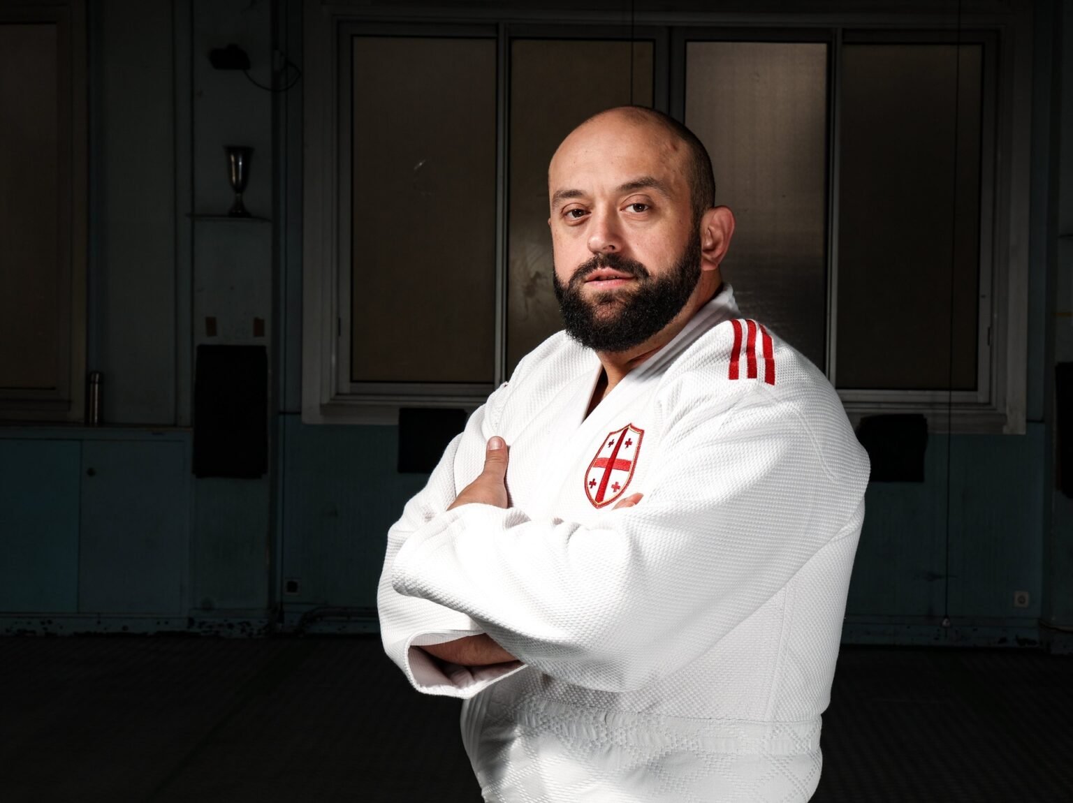 «Я люблю вас и верю в вас»: тренер Гуджеджиани готовит Грузию к домашнему чемпионату Европы Главный тренер сборной Грузии по дзюдо Лаша Гуджеджиани в кимоно со скрещёнными руками в тренировочном зале