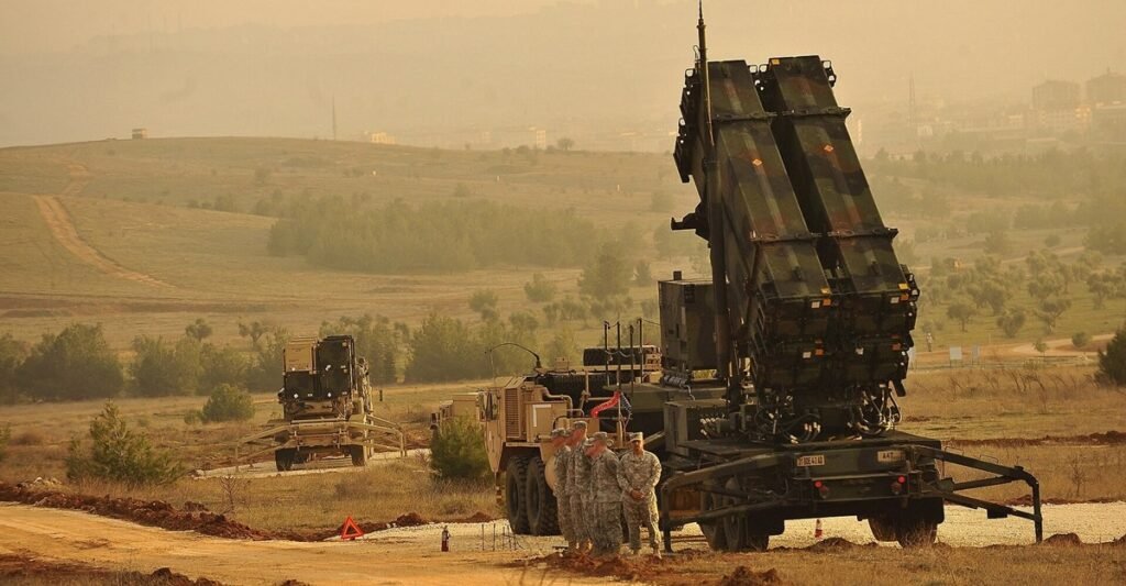 Зенитно-ракетный комплекс Patriot развёрнут на полевой позиции. Военнослужащие стоят рядом с пусковой установкой на фоне холмистой местности