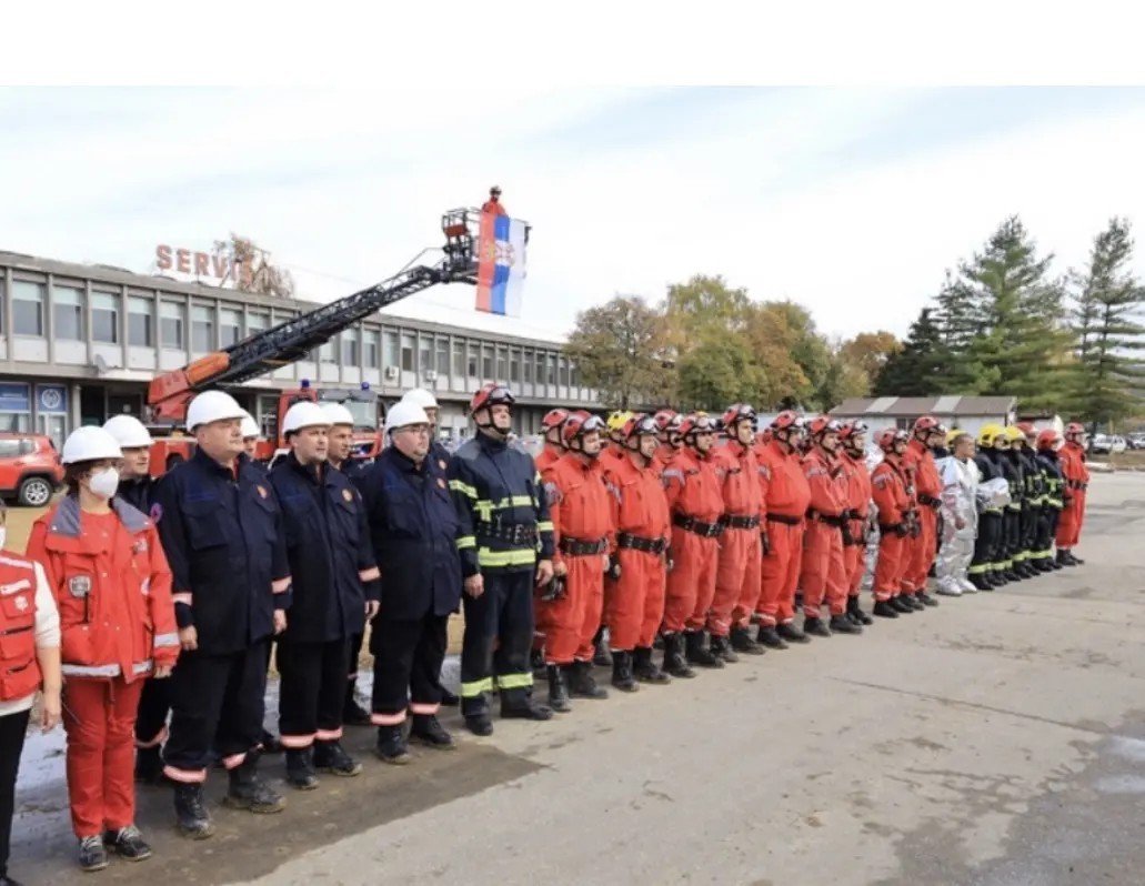 Построение сотрудников аварийных служб, включая пожарных и спасательные команды, с сербским флагом на пожарной лестнице. Фото: Glas Šumadije