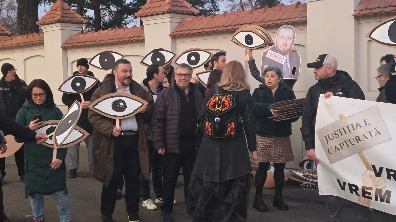 Протестующие с символическими «глазами» и плакатом «Юстиция захвачена» у ворот дворца Котрочень в Бухаресте