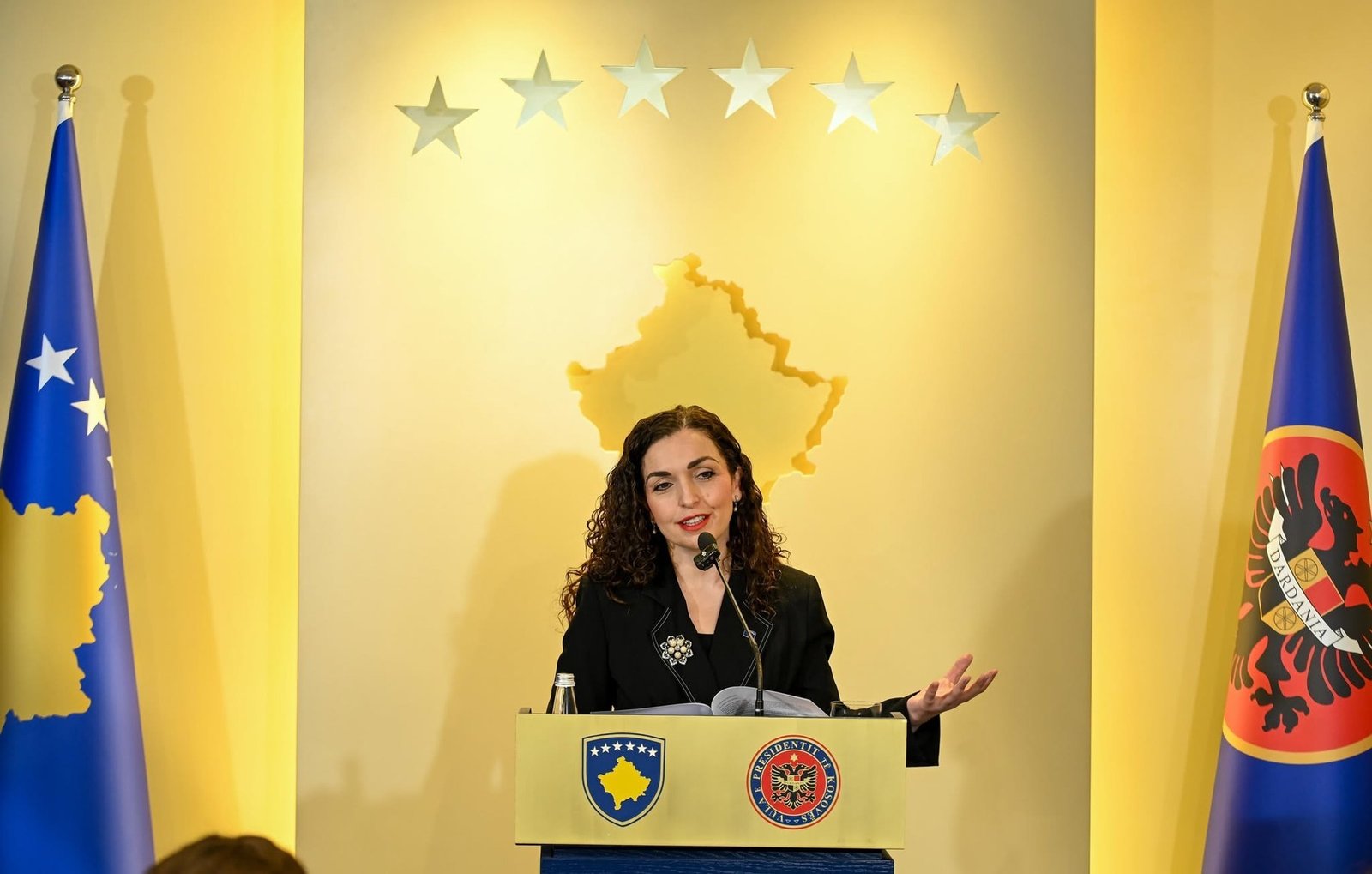 Президент Косово Вьоса Османи выступает на пресс-конференции за трибуной с символикой президента республики и государственными флагами