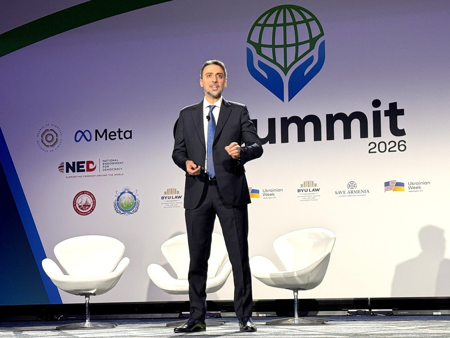 Выступление на Международном саммите религиозной свободы (IRF Summit) 2026 года в Вашингтоне. На заднем плане &mdash; логотипы организаторов, включая Save Armenia