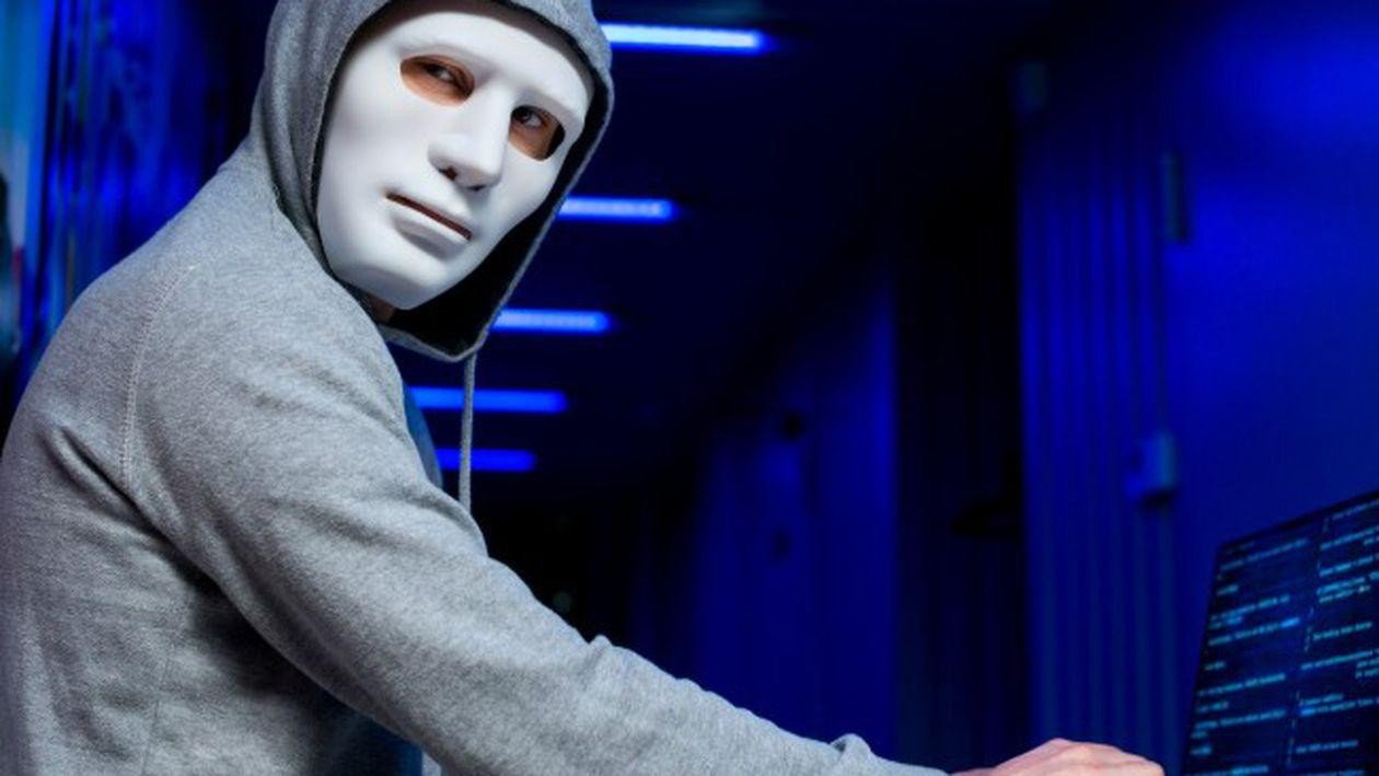 Хакер в маске в серверной комнате — символическое изображение киберугрозы для государственных учреждений Румынии
