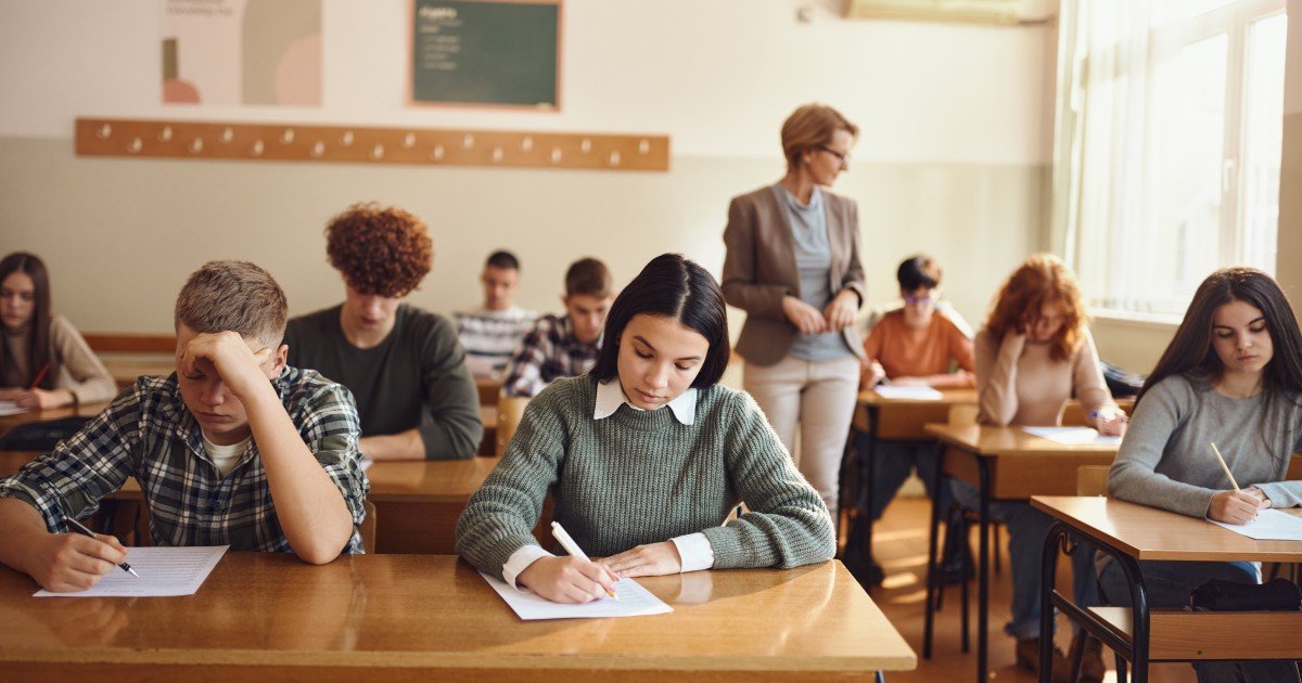 Ученики пишут экзаменационную работу в классе под наблюдением преподавателя