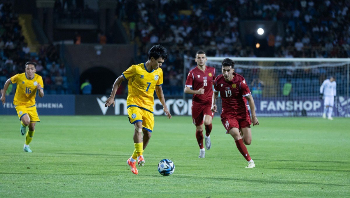 Игровой момент матча между сборными Армении и Казахстана: казахстанский футболист ведёт мяч, преследуемый армянским защитником