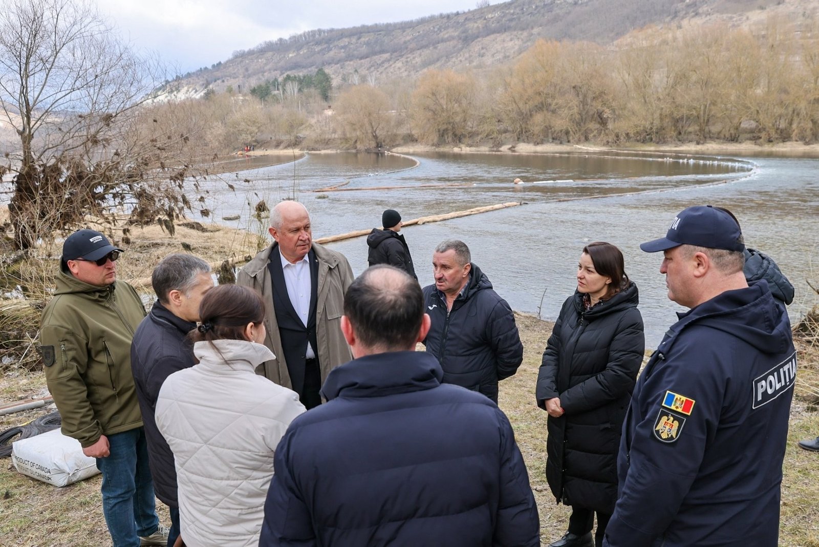 Чиновники и представители полиции осматривают заградительные бонны на берегу Днестра в районе села Арионешть
