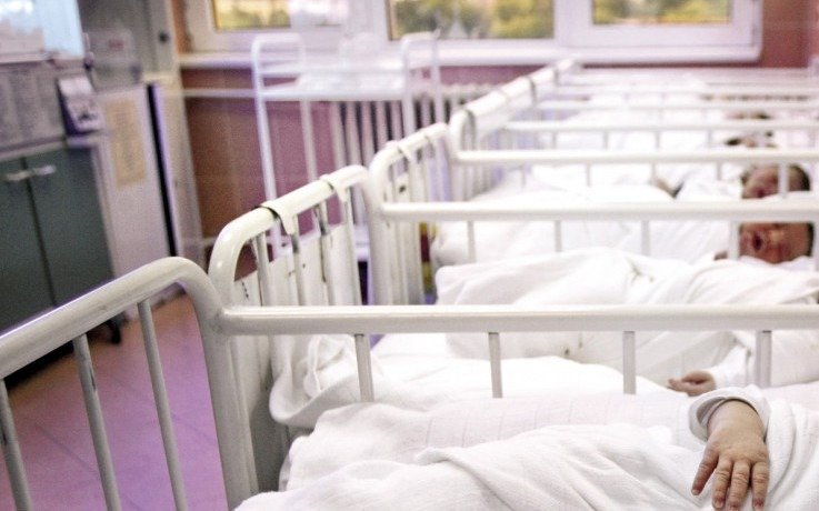 Новорождённые в кроватках родильного отделения больницы