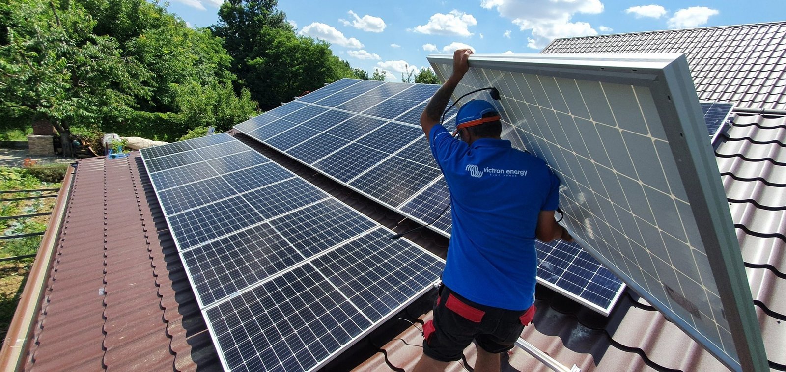 Рабочий устанавливает солнечные панели на крыше жилого дома — одно из требований обновлённой директивы ЕС по энергоэффективности зданий