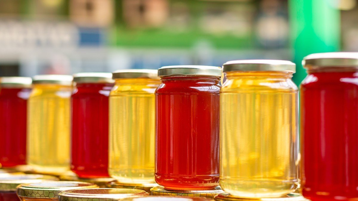 Банки с мёдом разных сортов — от светлого липового до тёмного каштанового — на рыночном прилавке