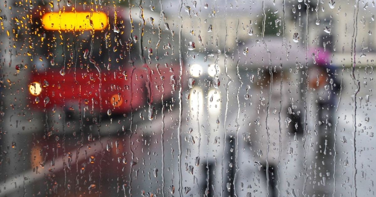 Дождевые капли на оконном стекле на фоне городского трамвая — непогода в Сербии