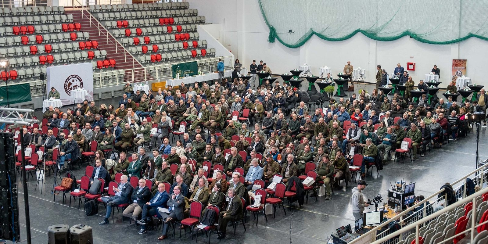 Вид сверху на конференц-зал с сотнями участников в красных креслах арены в Меркуря-Чук
