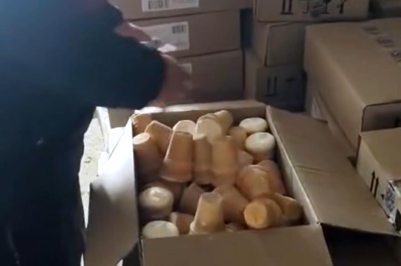 Инспектор проверяет упаковки мороженого в открытой коробке на пограничном контроле