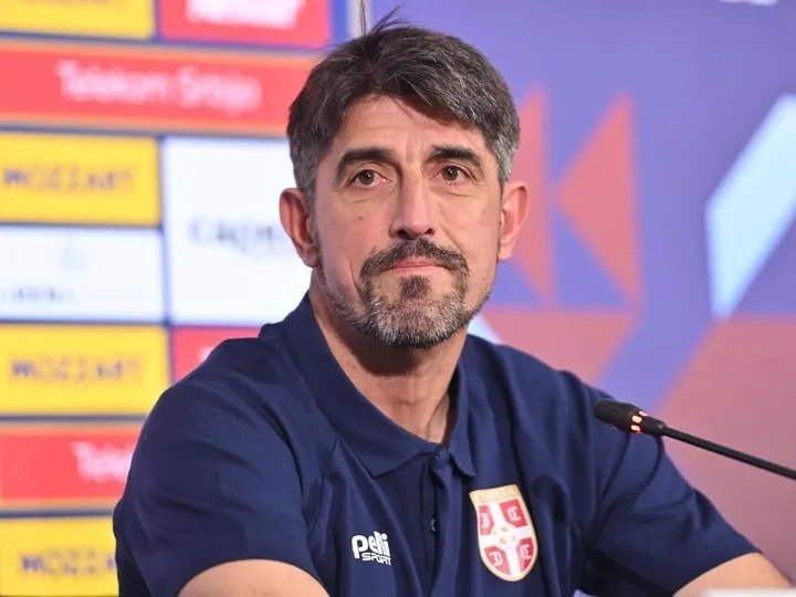 Главный тренер сборной Сербии Александар Паунович сидит перед микрофоном на пресс-конференции. На фоне баннеры спонсоров и надпись «Телеком Србија»