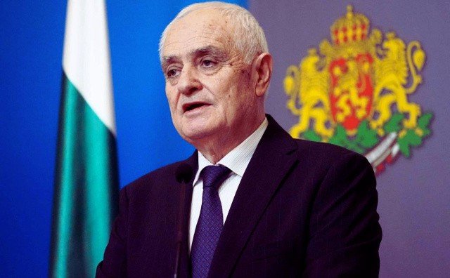 Министр обороны Болгарии выступает на трибуне с болгарским флагом и гербом. Фото: Novinite