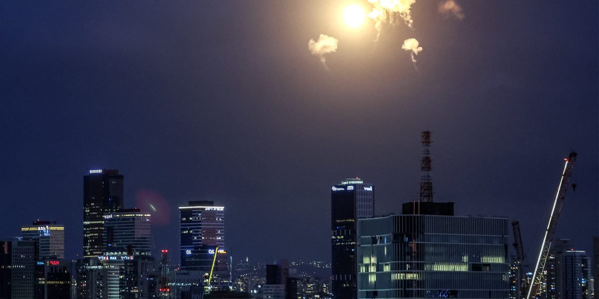 Night cityscape with bright flash/explosion in sky