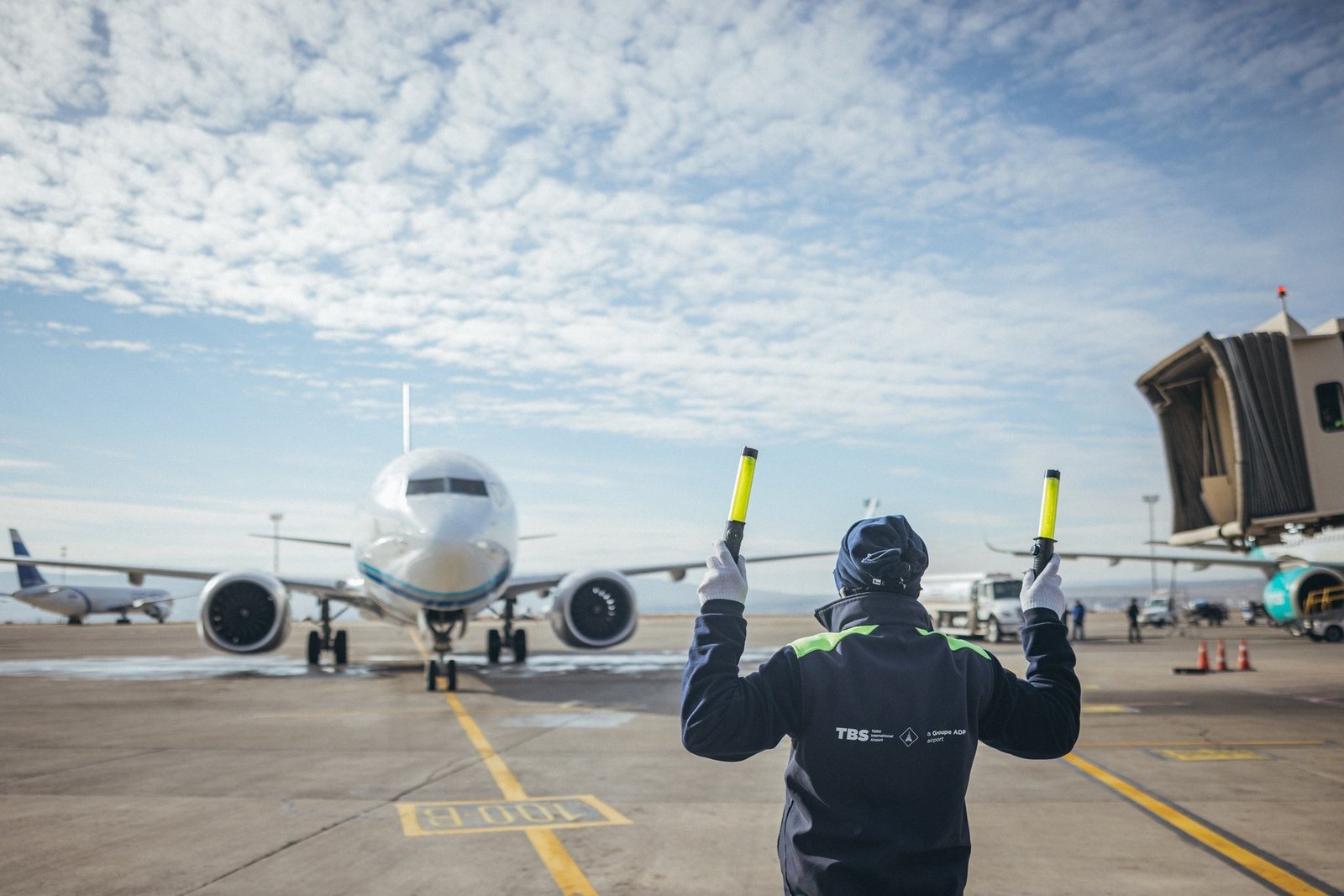 Сотрудник наземной службы направляет самолёт в Международном аэропорту Тбилиси