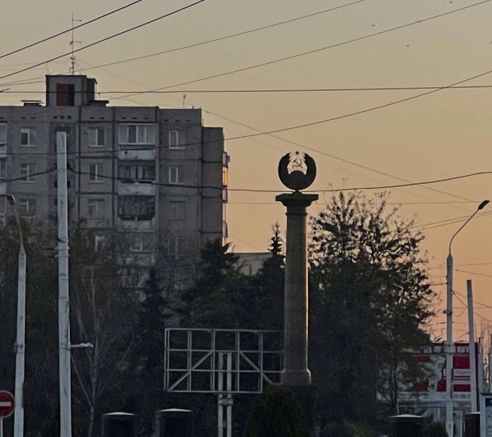 Городской пейзаж Приднестровья на закате с советским памятником серп и молот, жилой дом на заднем плане. Фото: Newsmaker.md