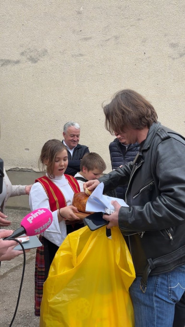 Ученица в народном костюме вручает Желько Митровичу традиционный хлеб-соль у школы в Марковице