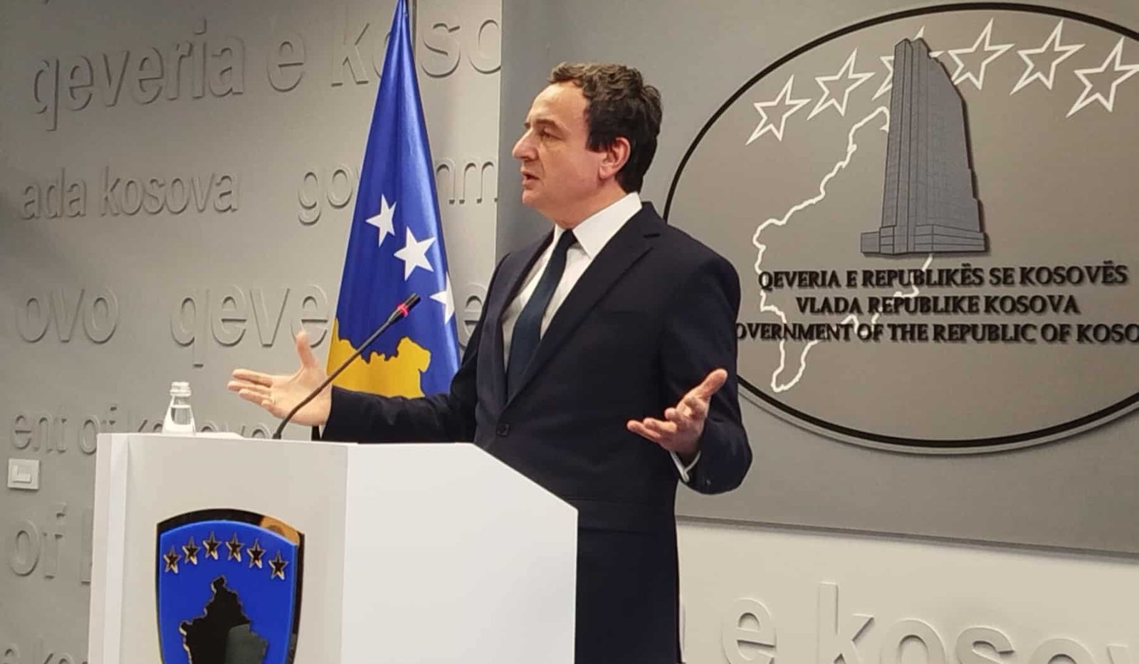 Премьер-министр Косово Альбин Курти выступает на пресс-конференции за правительственной трибуной на фоне эмблемы и флага республики