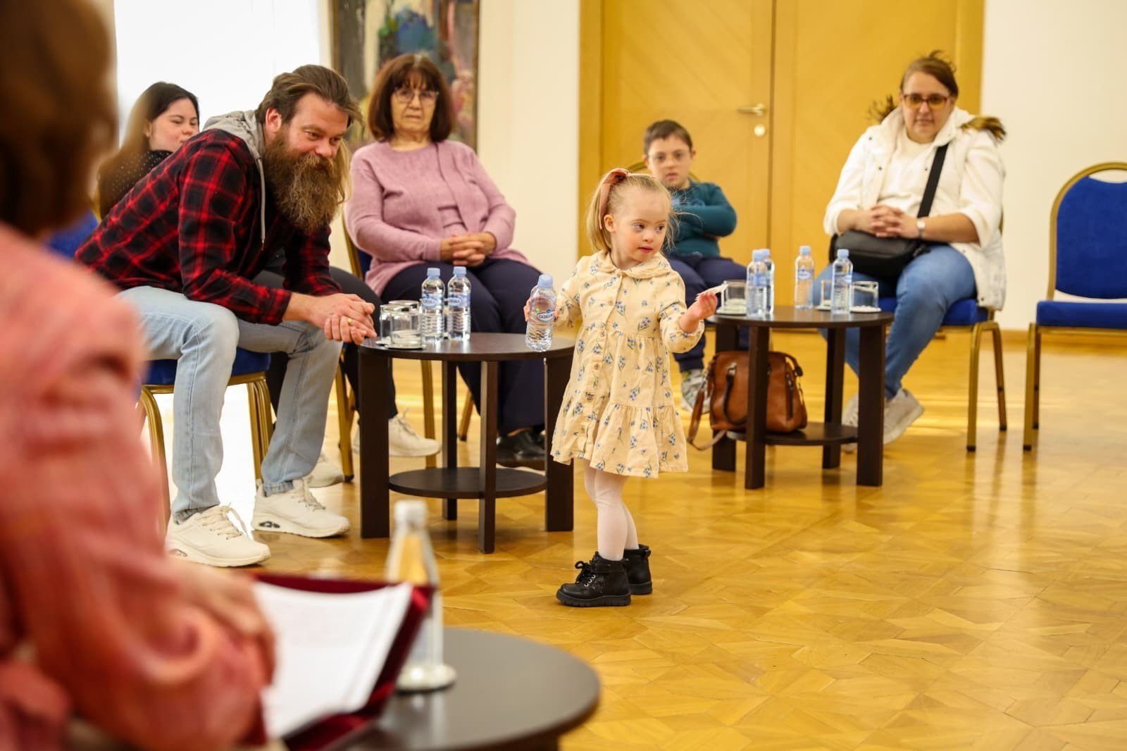 Маленькая девочка в нарядном платье танцует в центре зала на фоне сидящих гостей приёма в президентском дворце