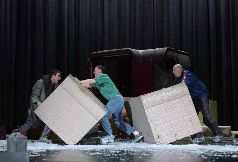 Сцена строительства баррикад — три актёра передвигают бетонные блоки в спектакле «Радио Сараево» в Ландестеатре Линца