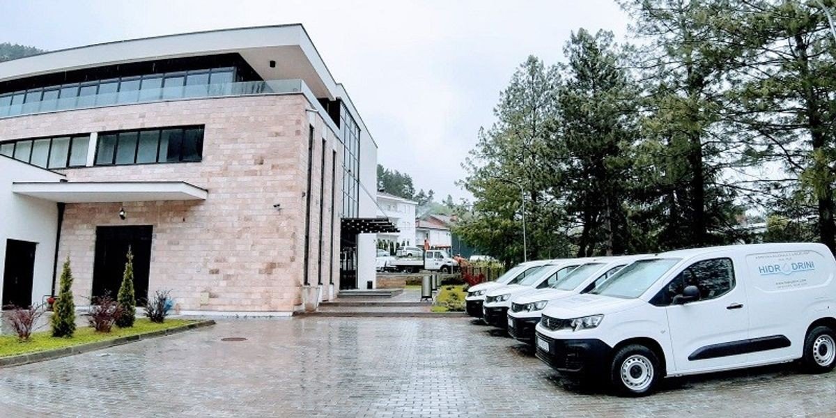 Здание водоснабжающего предприятия КРУ «Гидродрини» с фирменными автомобилями на парковке в Пече