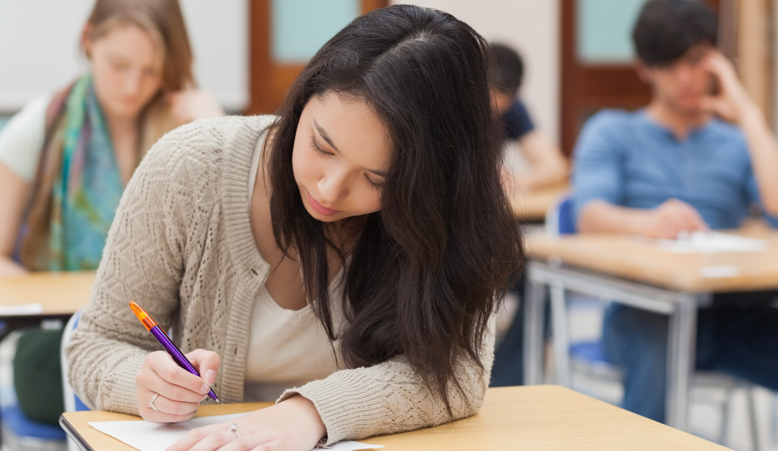 Ученица пишет контрольную работу за партой в классе