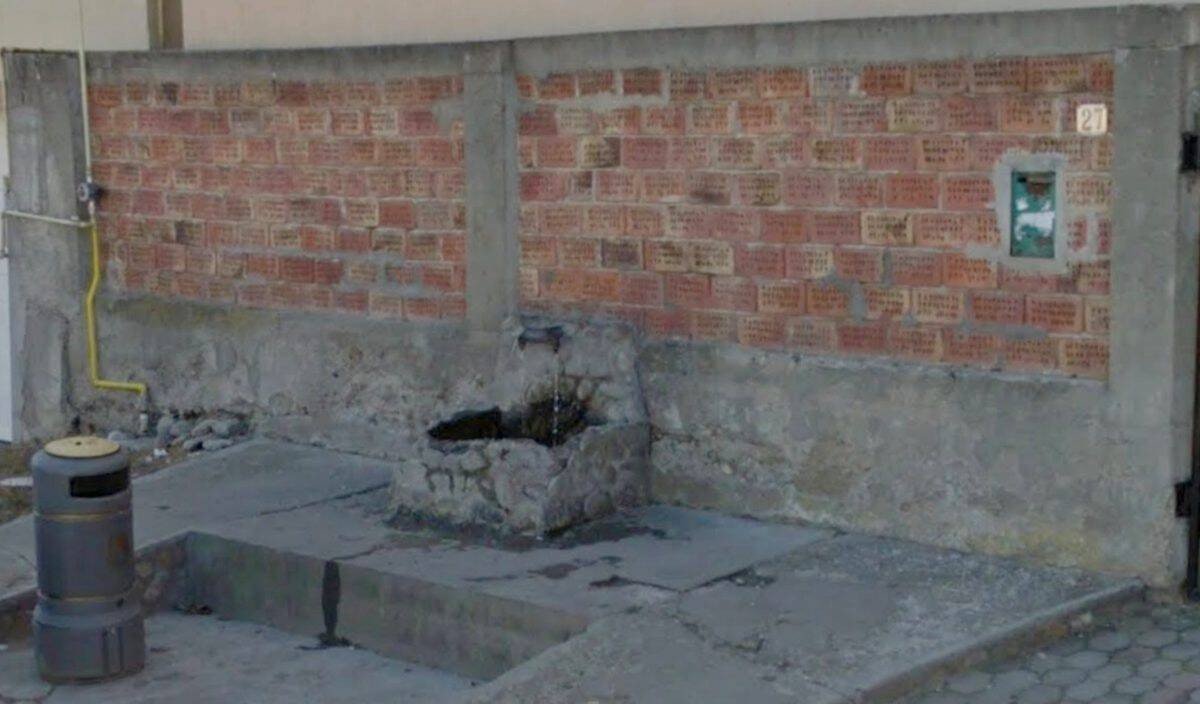 Общественный фонтан с источником воды у кирпичной стены в одном из населённых пунктов жудеца Алба