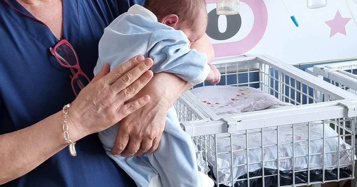 Медсестра держит новорождённого в родильном отделении больницы