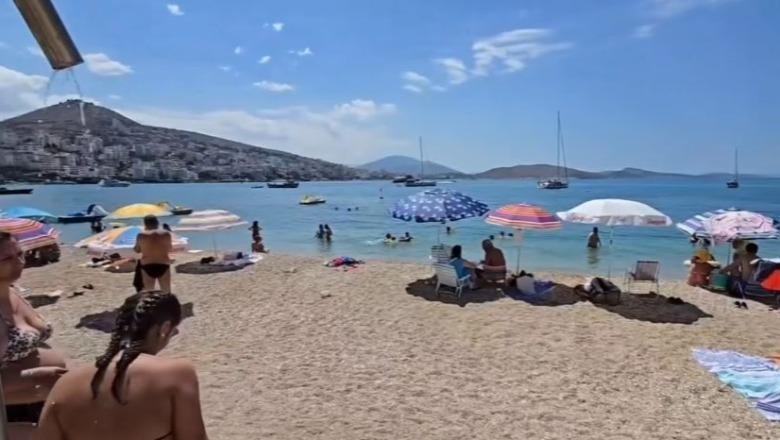 Туристы на пляже в Саранде с видом на горы и яхты в бухте