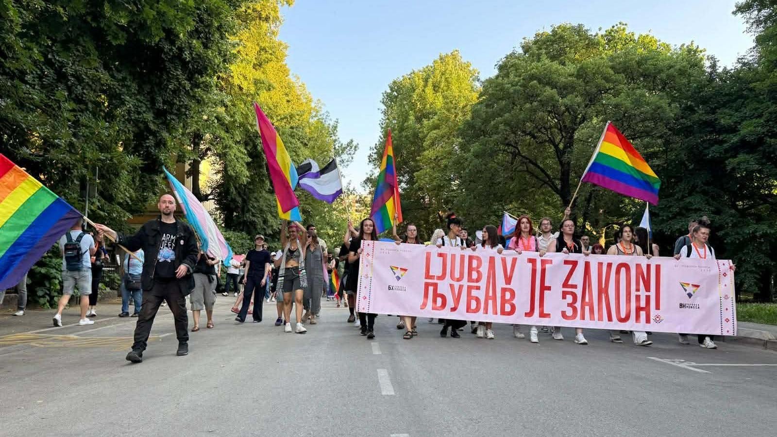Участники прайд-марша в Баня-Луке несут радужные и трансгендерные флаги и баннер с надписью «Любовь — это закон»