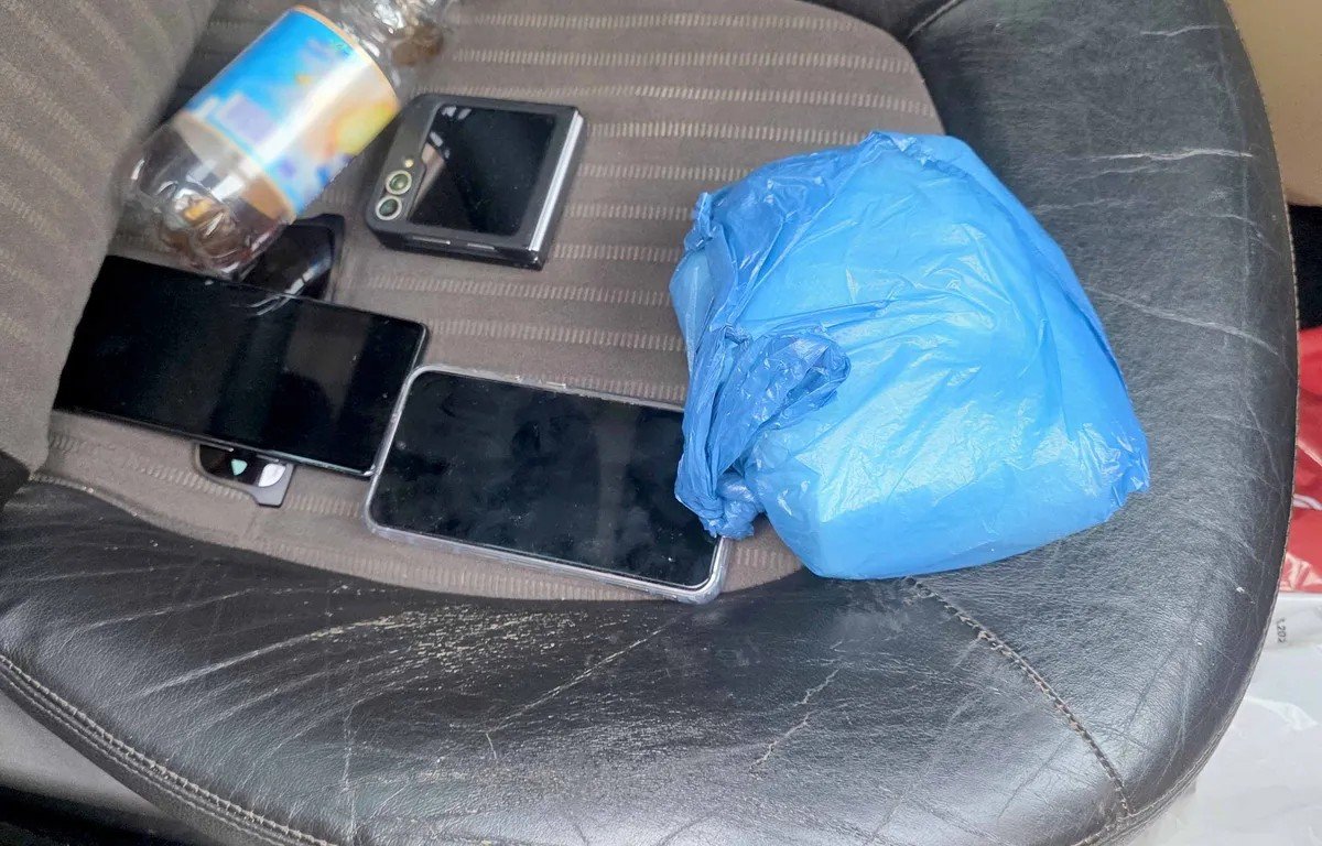 Multiple mobile phones and blue package on car seat - appears to be evidence photo. Фото: N1