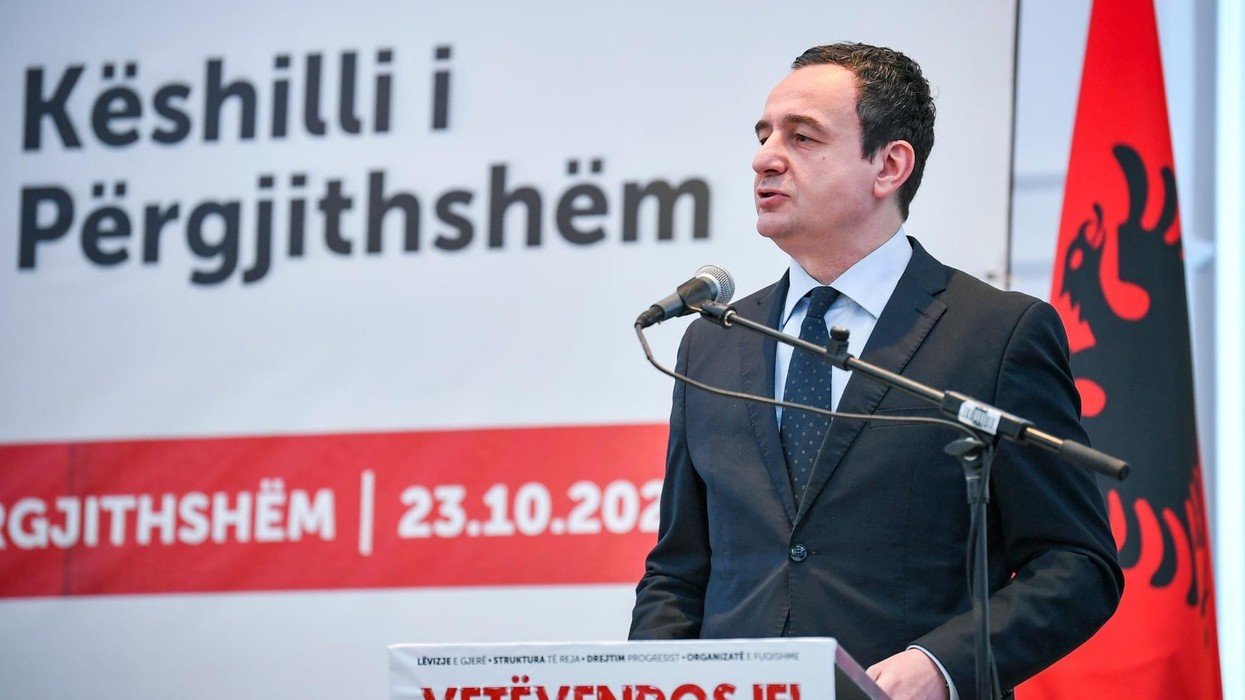 Kosovo PM Albin Kurti speaking at a podium with Albanian flag in background