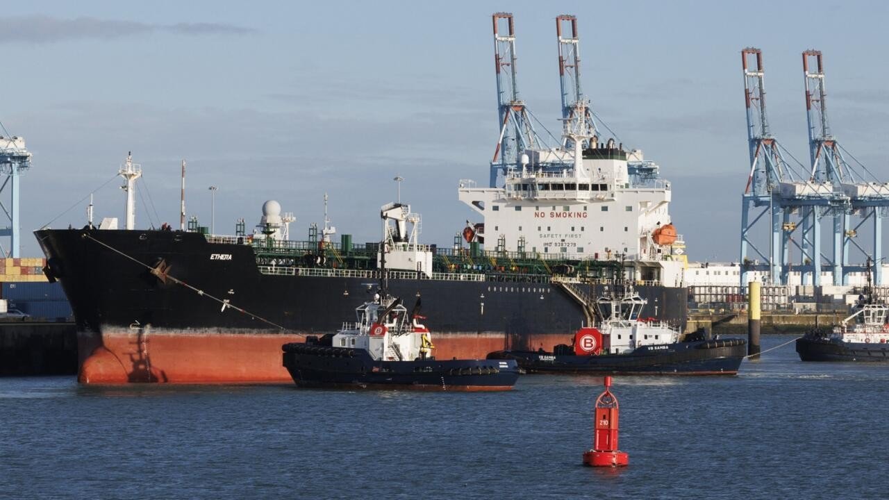 Танкер Ethera в сопровождении буксиров в порту, на заднем плане краны и контейнеры. Фото: France 24