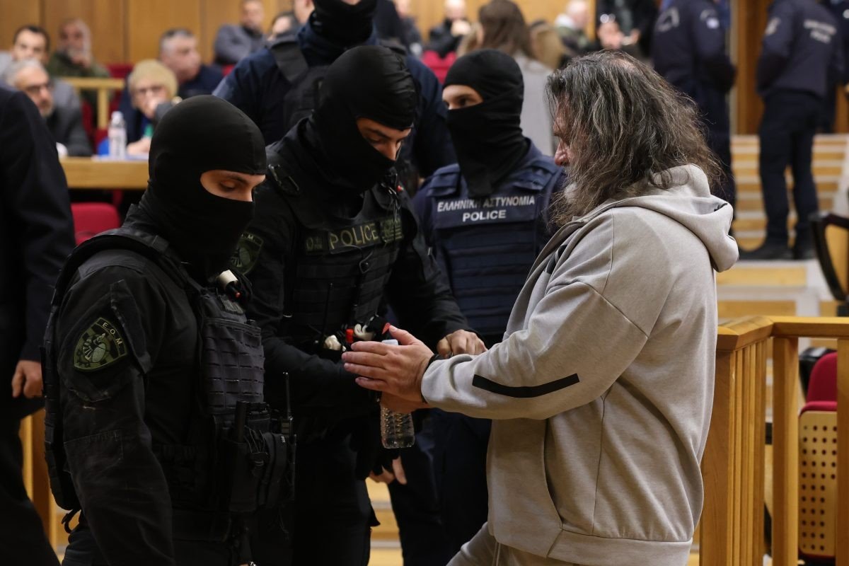 Подсудимому надевают наручники сотрудники полицейского спецназа в зале суда по делу «Хриси Авги»